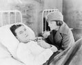 Young woman looking at a locked of a young man who is lying on the bed in a hospital Royalty Free Stock Photo