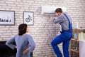 Woman Looking At Technician Repairing Air Conditioner Royalty Free Stock Photo