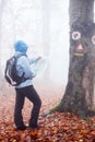 Young woman looking at the map while hiking through a forest on a foggy day Royalty Free Stock Photo