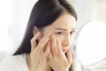 Young woman looking at  mirror and checking the  acne problem at home Royalty Free Stock Photo