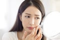 Young woman looking at  mirror and checking the  acne problem at home Royalty Free Stock Photo