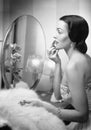 Young woman looking into a mirror and putting on make up Royalty Free Stock Photo