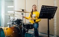 Young woman looking at music notes while playing drums. Lesson at the music school. Royalty Free Stock Photo