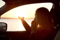 Woman looking out car window of the sunset on the sea and talking on the phone. Royalty Free Stock Photo