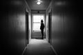 Young woman looking out a window in a dark hallway.