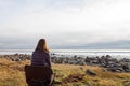 A young woman looking at the rocky beach sitting alone in a chair Royalty Free Stock Photo