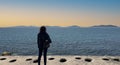 Young woman looking at sea at sunset, lonely young girl standing alone at seashore, looking at horizon over calm ocean. Royalty Free Stock Photo