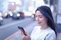 Young Woman looking at smart phone in the city at night Royalty Free Stock Photo