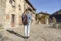 Young woman looking smart phone walking with fashion jeans jacket and backpack.Tourist traveling concept in old medieval village Royalty Free Stock Photo