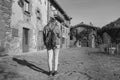 Young woman looking smart phone walking with fashion jeans jacket and backpack.Tourist traveling concept in old medieval village Royalty Free Stock Photo