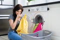 Woman Looking At Smelly Clothes Out Of Washing Machine Royalty Free Stock Photo