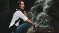 Young woman looking at splashing jungle waterfall