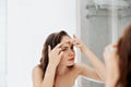 Young woman  looking and squeeze  acne on a face in front of the mirror. Ugly problem skin girl, teen girl having pimples Royalty Free Stock Photo