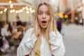 Young woman looking surprised at camera shocked by sudden win good victory news, wow in city street Royalty Free Stock Photo