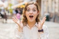 Young woman looking surprised at camera shocked by sudden win good victory news, wow in city street Royalty Free Stock Photo