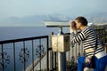 Young woman looking through telescope at sea viewpoint Royalty Free Stock Photo