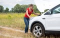 Young woman looking under the hood of broken car and trying to fix it Royalty Free Stock Photo