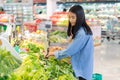 Young woman looking at vegetables at grocery store. female shopping in supermarket. Customer buying vegetables at the market