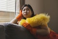 Young woman looking at the window, sitting on the sofa, tired of doing housework, daily work that has to be done every day Royalty Free Stock Photo