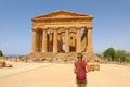 Young woman looks at Concordia Temple in the Valley of the Temples Agrigento, Sicily. Traveler girl visits Greek Temples in Royalty Free Stock Photo