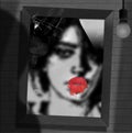 A young woman looks at her reflection in a mirror. A smudged red lipstick print of lips is on the mirror Royalty Free Stock Photo