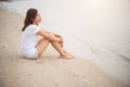 Young woman with looks lonely feel sit on the beach. Looking away to the sea.