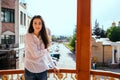 A young woman looks out from the balcony.The bright sun illuminates the girl. Beautiful brunette enjoys the sun