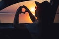 A young woman looks out the car window at the sunset on the sea.	heart made with hands Royalty Free Stock Photo