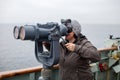 A young woman looks out through ship binoculars out into the open ocean