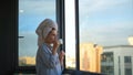 Young woman looks out window and drinks coffee in morning. Concept. Beautiful woman starts day with cup of coffee and Royalty Free Stock Photo