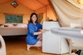 Young woman looks into the refrigerator during vacation in modern glamping tent. Luxury camping tent for outdoor recreation