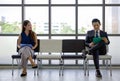 Young woman looks and smiles at a man sitting further away. Asian business people waiting for job interview by sitting spaced Royalty Free Stock Photo