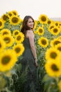 Young woman looks smiling standing against sunflower field Royalty Free Stock Photo