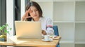 A young woman looks tired using a laptop. She is serious about research to graduate