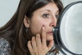 Young woman looks worried in the mirror at the pimple on her face Royalty Free Stock Photo