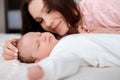 Young woman lovingly looks at her sleeping newborn daughter in the bedroom Royalty Free Stock Photo