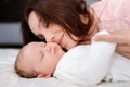 Young woman lovingly looks at her sleeping newborn daughter in the bedroom Royalty Free Stock Photo