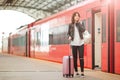 Young woman with luggage talking by cellphone at a train station. Caucasiam tourist waiting her express train while her Royalty Free Stock Photo