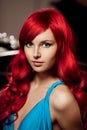 Young woman with luxurious long beautiful red hair in a blue fashionable evening dress in the rich interior. Royalty Free Stock Photo