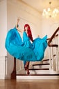 Young woman with luxurious long beautiful red hair in a blue fashionable evening dress in the rich interior. Royalty Free Stock Photo