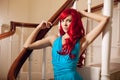 Young woman with luxurious long beautiful red hair in a blue fashionable evening dress in the rich interior. Royalty Free Stock Photo