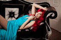 Young woman with luxurious long beautiful red hair in a blue fashionable evening dress in the rich interior. Royalty Free Stock Photo