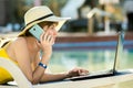 Young woman lying on beach chair working on computer laptop connected to wireless internet having conversation on mobile sellphone Royalty Free Stock Photo