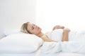 Young woman lying in the bed. Beautiful blond sleeping girl. Morning in the bedroom, daylight from the window. Health Royalty Free Stock Photo
