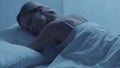 Young woman lying in the bed at night. Beautiful blond sleeping girl. Twilight in the bedroom, moonlight from the window