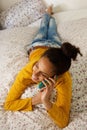 Young woman lying in bed and talking on cell phone Royalty Free Stock Photo