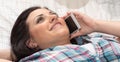 Young woman lying on bed and talking on mobile phone Royalty Free Stock Photo