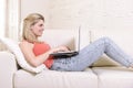 Young woman lying comfortable on home sofa using internet in laptop computer smiling happy Royalty Free Stock Photo