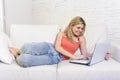 Young woman lying comfortable on home sofa using internet in laptop computer smiling happy Royalty Free Stock Photo