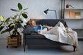 Young woman lying on cozy couch and reading a book Royalty Free Stock Photo